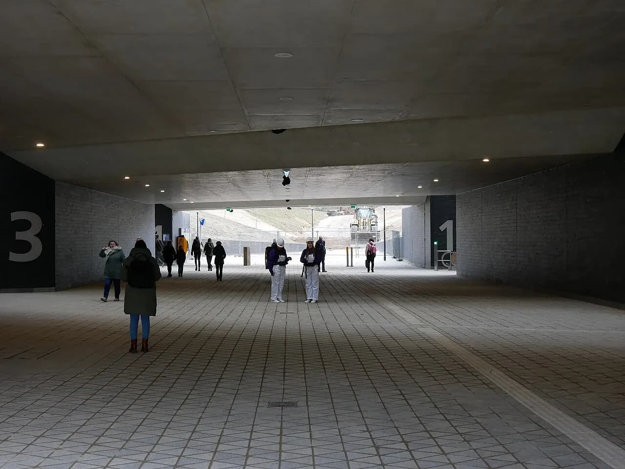 Travelers in the concrete East tunnel of Ede-Wageningen station.