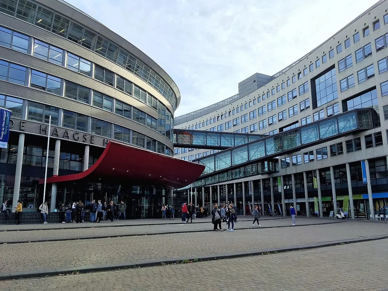 The curved brick facades and glass skybridge of The Hague University of Applied Sciences.